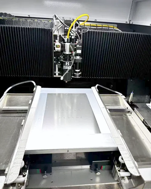 Fiber laser cutting head cutting apertures into a stainless steel stencil sheet